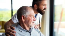 A senior patient and a caregiver looking out the window
